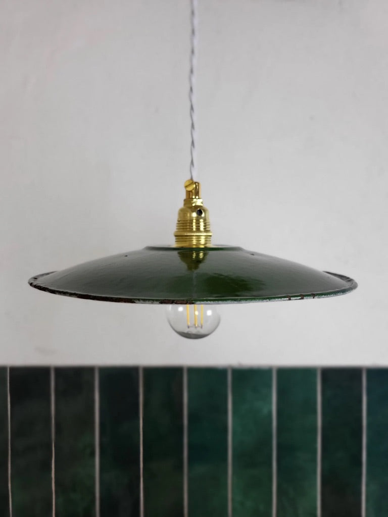 Suspension émaillée vintage avec lumière dirigée vers le bas, ambiance atelier rétro et industrielle.