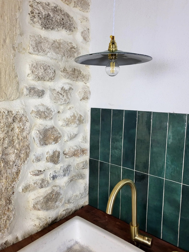 Suspension émaillée vintage avec lumière dirigée vers le bas, ambiance atelier rétro et industrielle.