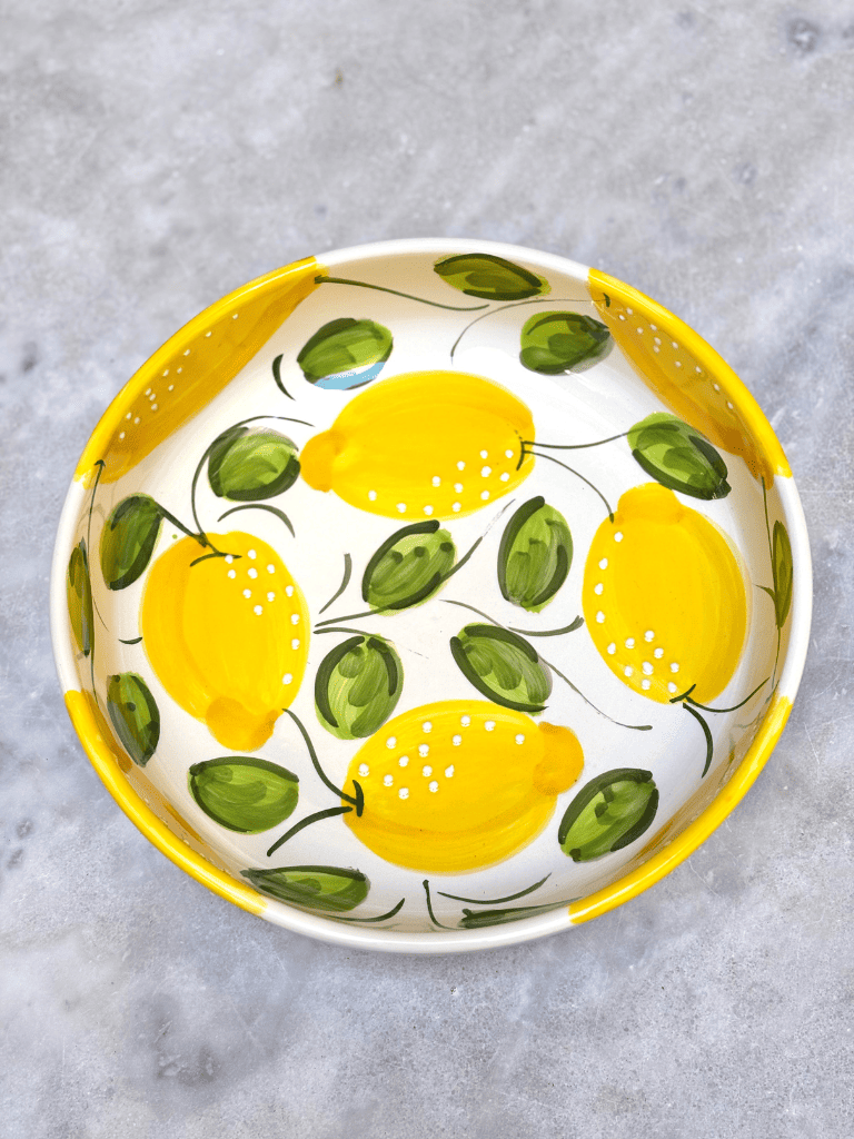 Vue aérienne du plat rond à bord en céramique artisanale, motifs citrons méditerranéens, saladier, plateau à fruit, plat de présentation en poterie.