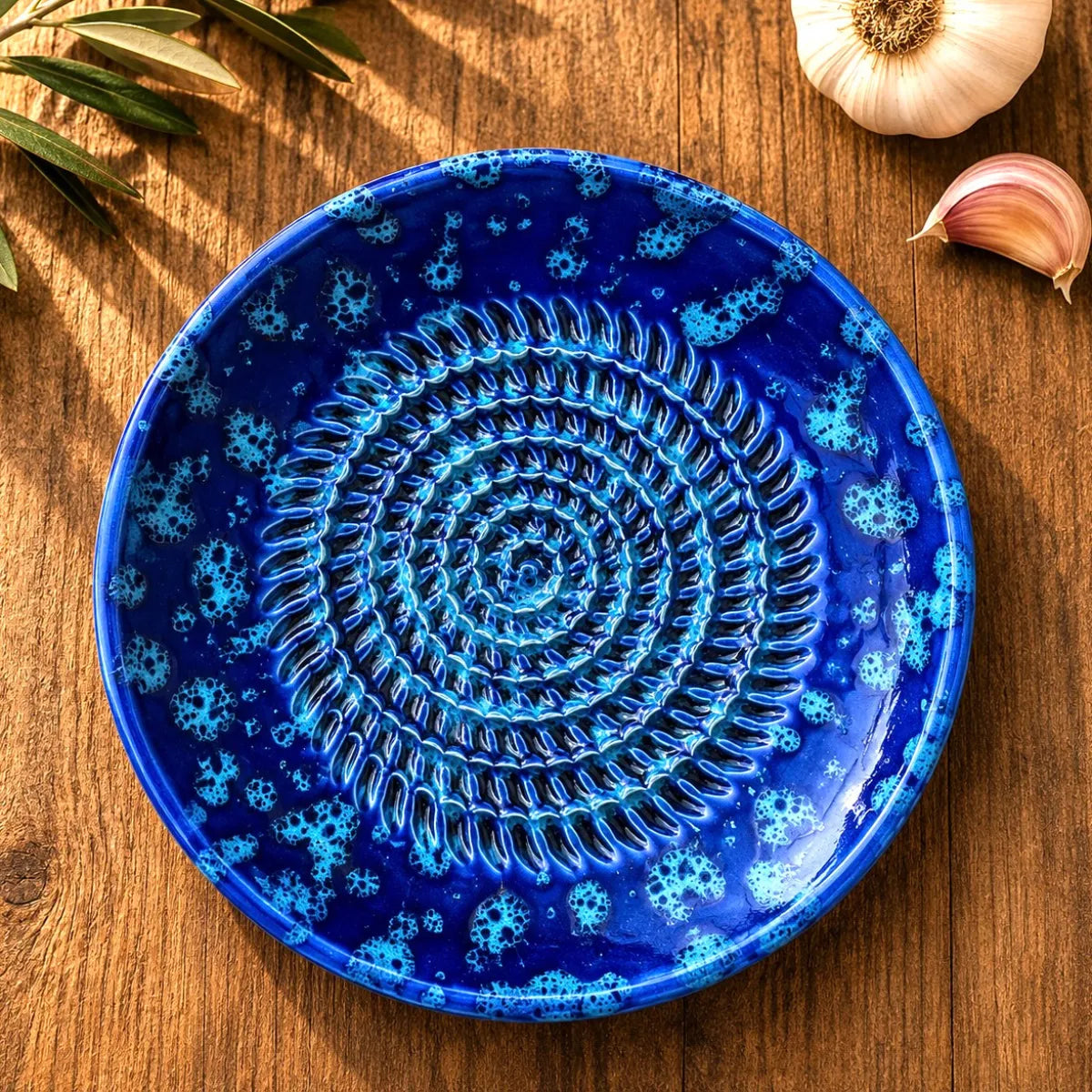 râpe à ail en céramique bleu méditerranéen sur table en bois
