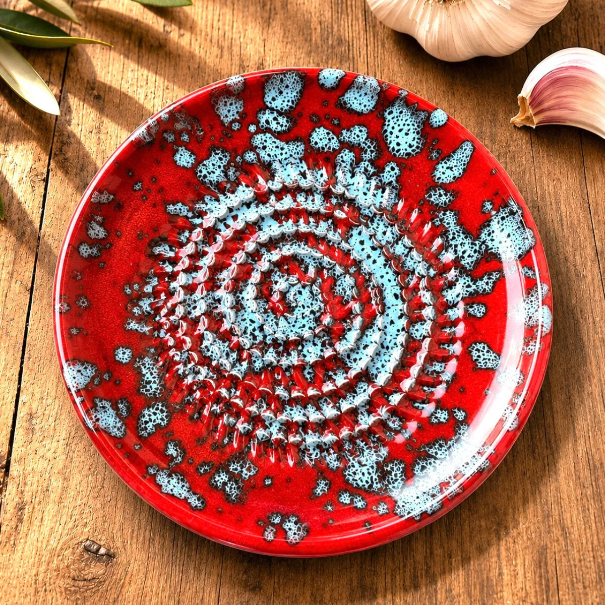 Gratte ail, légume, gingembre en poterie rouge sur table en bois