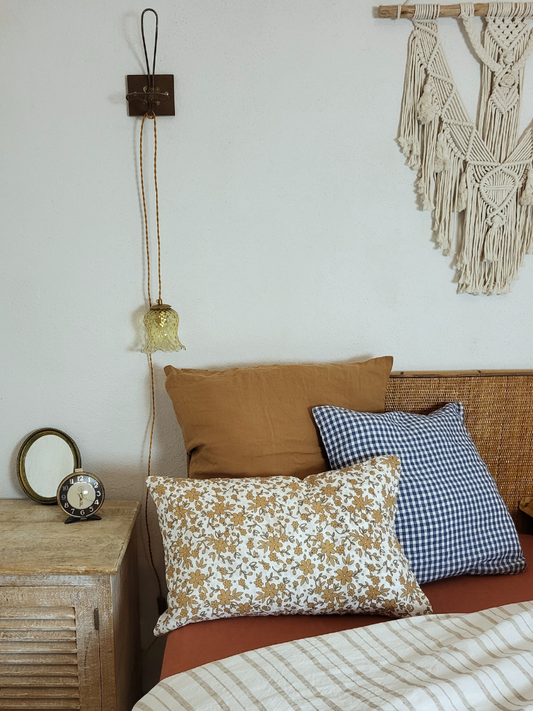 Lampe baladeuse ambre suspendue au dessus d'un lit avec des coussins