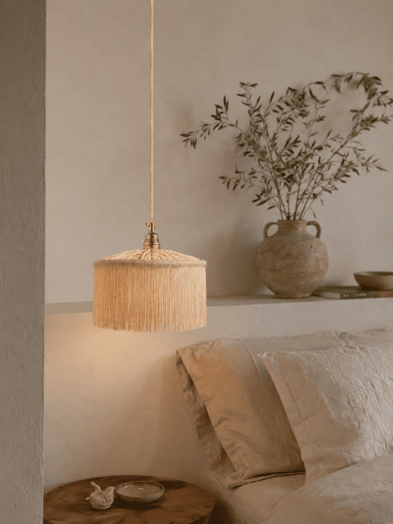  abat-jour en raphia tissé main avec franges, vue du dessous sur fond sombre, ambiance bohème naturelle et chic.