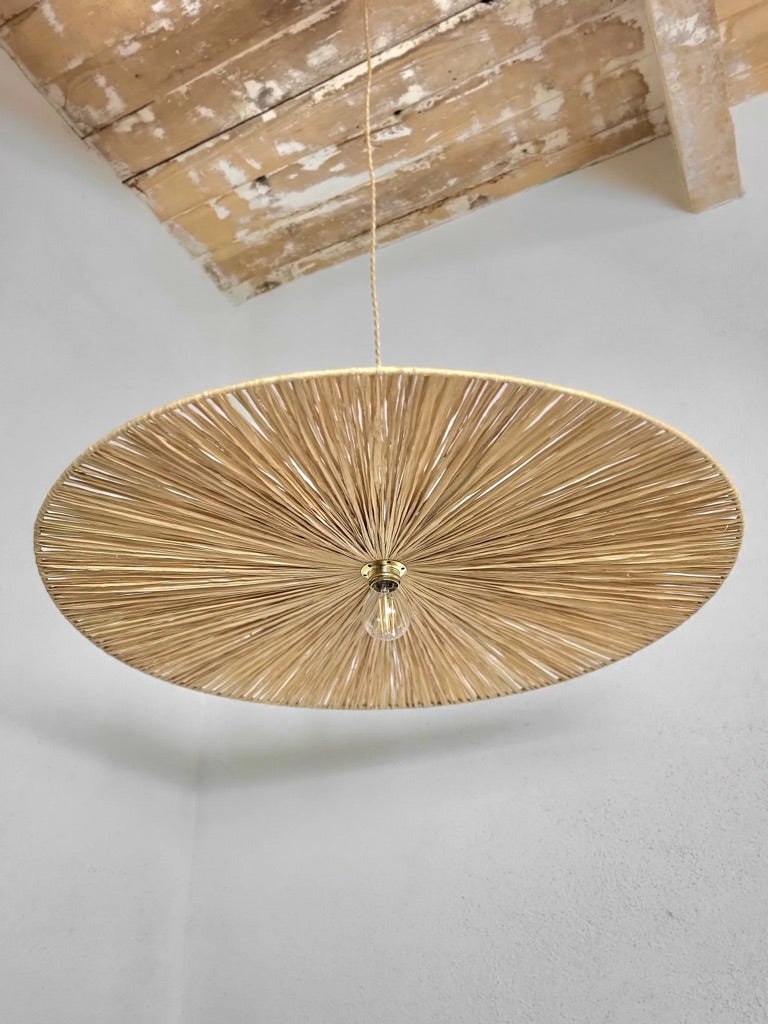Vue du dessous d’un luminaire artisanal en raphia, tressage ajouré laissant passer la lumière.