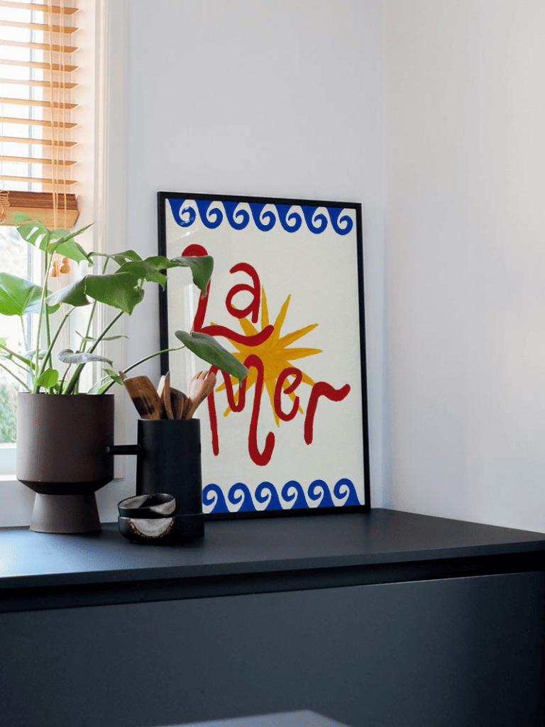 Affiche La Mer encadrée dans un salon lumineux à la décoration bord de mer, avec tons bleus et naturels