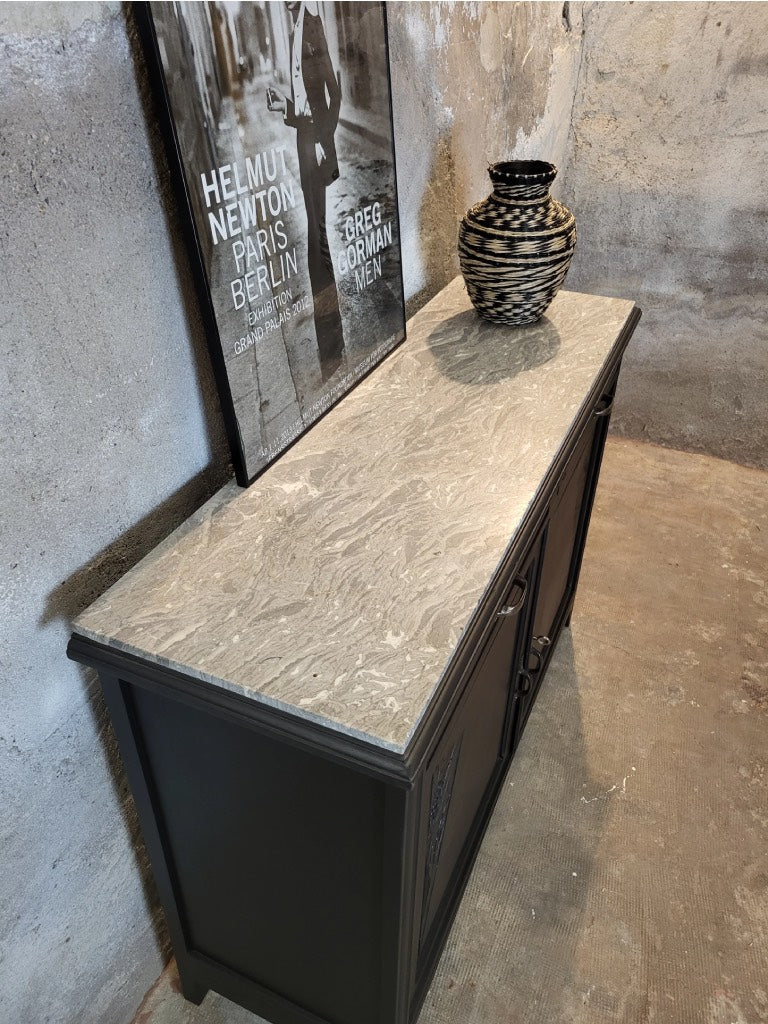 Zoom sur le plateau en marbre du buffet, au ton gris veiné de blanc, apportant contraste et raffinement.