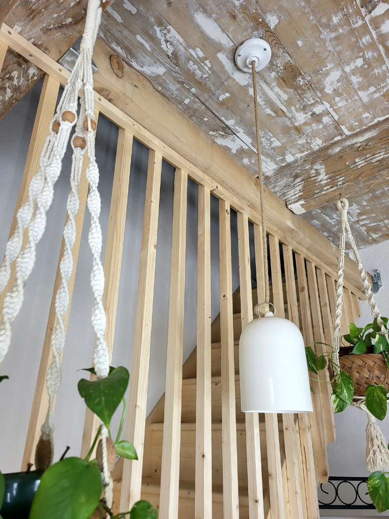 Suspension en céramique blanche installée près de tasseaux de bois et de plantes vertes suspendues sur du macramé, éclairage vertical élégant avec un intérieur contemporain