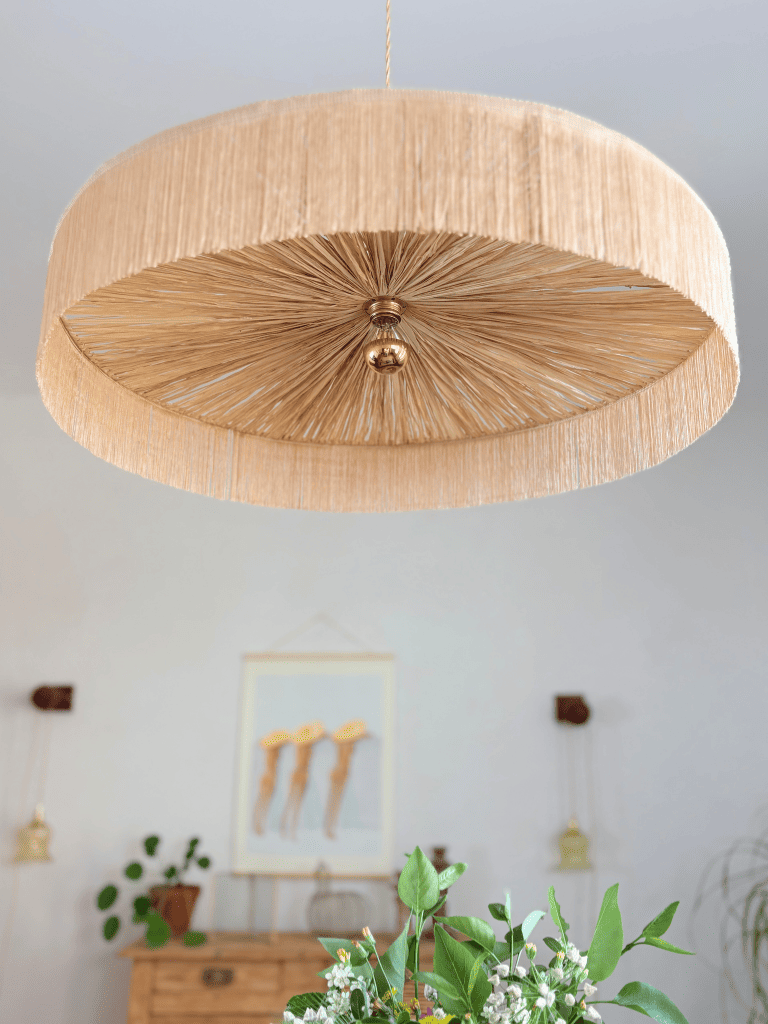 Vue du dessous de la grande suspension Parasol en raphia et franges made in France, mise en situation dans un décoration méditerranéenne.