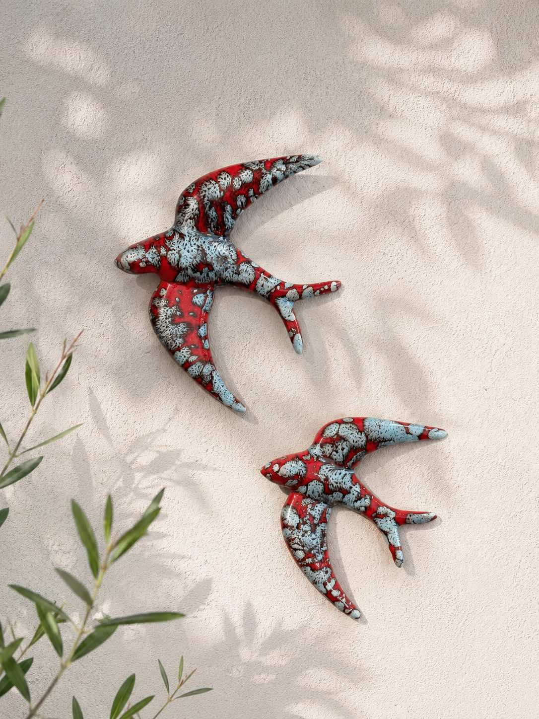 Oiseaux en céramique avec leurs ailes incurvées, de couleurs rouge avec son bleu craquelé. Idéal pour une décoration méditerranéen. A fixer au mur ou à planter dans un jardin. 