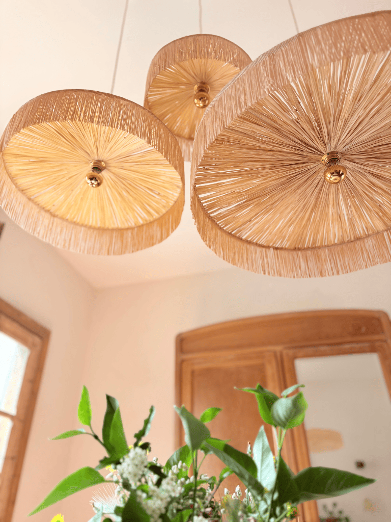 Luminaire en raphia naturel vu du dessous, trois abat-jours de tailles différentes avec franges, fabriqué en France artisanalement.