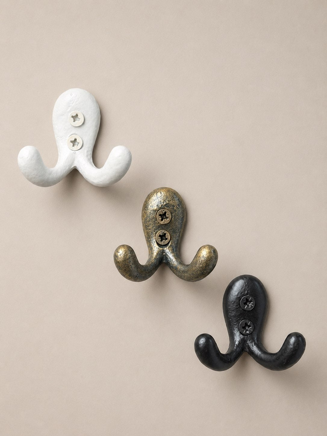 Trois patères en métal, de couleur blanche, doré et noir. Fixation murale, idéal pour faire porte manteaux, porte serviette, porte clés ou encore porte torchon dans la cuisine, salle de bain et entrée.