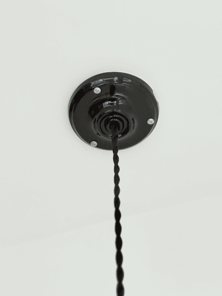 détail de la rosace en porcelaine noire et du câble torsadé noir à l'esprit vintage de  ce luminaire en céramique noire