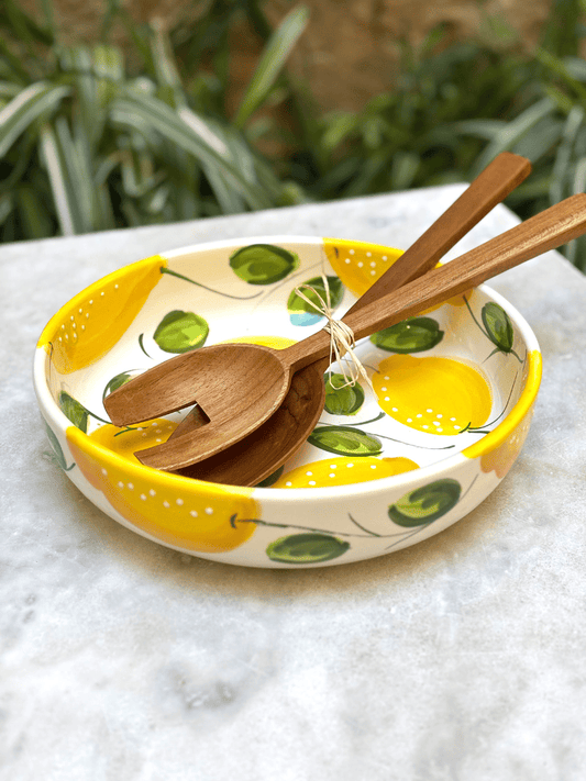 Plat rond à bord en terre vernissée décoré de citrons, posé sur une table de repas, ambiance méditerranéenne et colorée, couvert