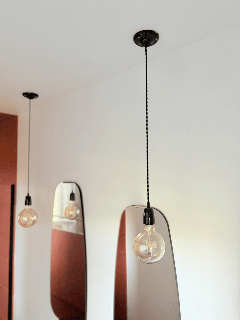 suspension en porcelaine noire dans une salle de bain. Plafonnier et douille en céramique noire, câble torsadé noir style vintage. 
