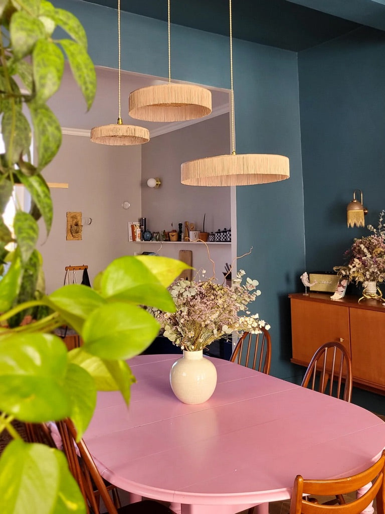 Suspension trio en raphia naturel et franges, design inspiré des parasols, dans salle à manger chic et colorée.